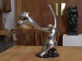 une statue en argent posée sur une table en bois dans une pièce
