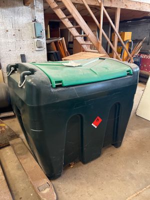 a large green container sitting on the floor next to a pile of wood