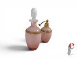 pair of pink glass perfume bottles with gold trim on a white background
