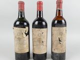 trois bouteilles de vin sont posées côte à côte sur une surface blanche