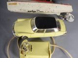a yellow toy car next to a toy boat and a yellow phone