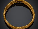 un bracelet en or avec un motif tressé sur fond noir