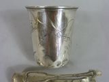 une tasse en argent et une cuillère sur une table blanche