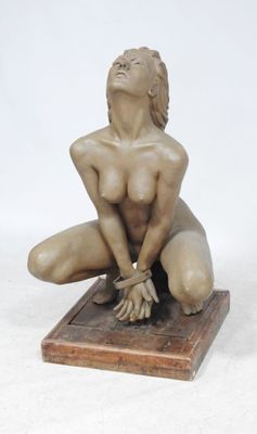 statue d'une femme nue assise sur un socle en bois, les mains posées sur les genoux
