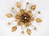 a gold flower with leaves on it on a white surface