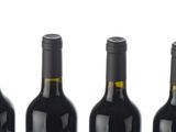 six bottles of wine are lined up in a row on a white surface