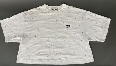 a white t - shirt with black dots on the front and a small black dot on the back