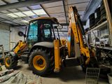 a backhoe of a yellow tractor in a garage