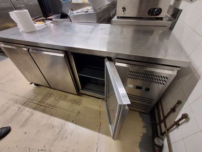 un plan de travail en acier inoxydable dans une cuisine équipée de deux fours