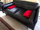 a black leather couch with red pillows in a living room