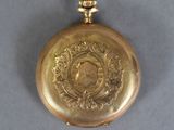 a gold pocket watch on a gray surface
