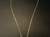 a gold necklace with a black and white bead on it