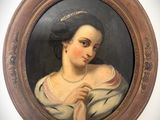 un tableau ovale représentant une femme portant un collier de perles, dans un cadre marron