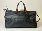 the large black leather bag is sitting on a white surface