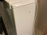 un petit réfrigérateur blanc dans le coin d'une pièce