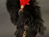 black and red military hat with red feathers on top of a mannequin head