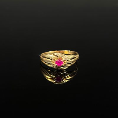 un gros plan d'une bague en or avec une pierre rose au centre