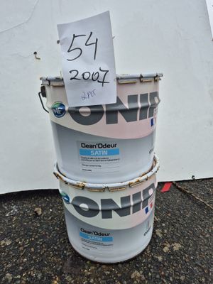 trois seaux de peinture posés par terre, sur lesquels est accrochée une pancarte
