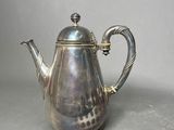 a silver tea pot with a handle on a table