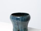 une image représentant un vase bleu posé sur une surface blanche