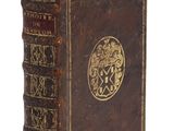 un vieux livre avec une couverture plaquée or sur fond blanc