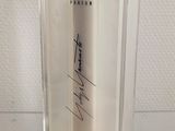 an image of a bottle of perfume with a signed label