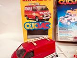 a red toy truck and a red car next to a box of toys