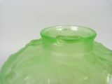 a green glass vase sitting on a white surface