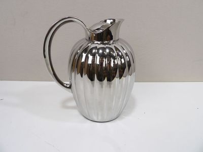 a silver pitcher sitting on a table with a white background