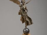 une statue en bronze représentant un ange, posée sur un socle en marbre