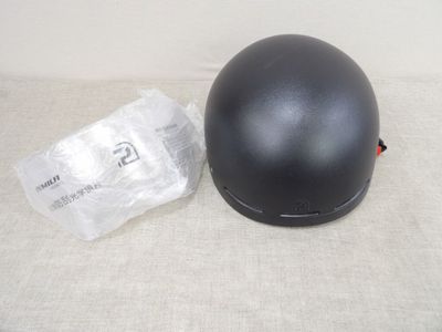 une image représentant un casque de moto noir posé sur une surface blanche