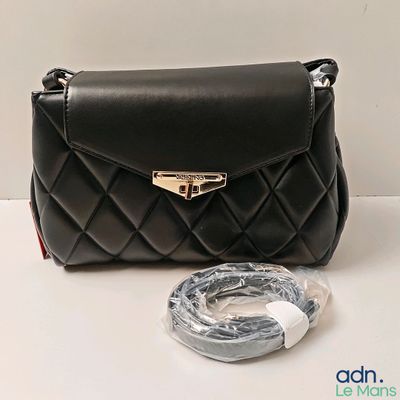 un sac à main noir et une ceinture posés sur une table blanche