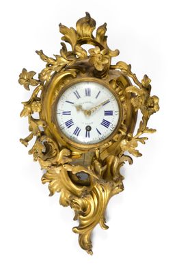 une horloge dorée accrochée à un mur blanc, sur fond blanc