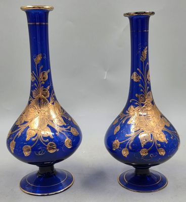 une paire de vases bleus ornés de motifs dorés sur fond blanc