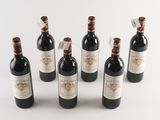 six bottles of wine are lined up in a row on a white surface