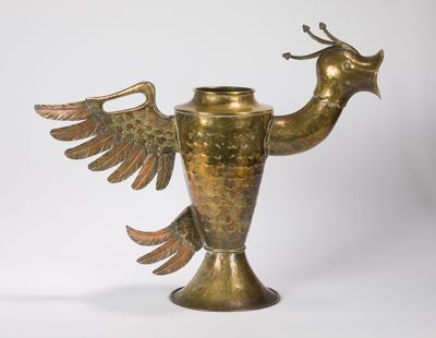 une image représentant un vase en laiton sur lequel est représenté un oiseau