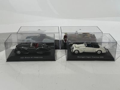 deux modèles réduits de voitures en noir et blanc, présentés dans des vitrines transparentes posées sur un fond blanc