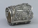 an antique silver cuff bracelet with intricate design on a gray background