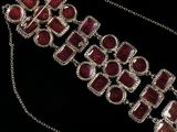 a close up of a necklace with red stones on a black background