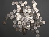 a pile of silver coins on a black surface