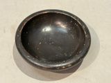 a black bowl sitting on a table with a white table cloth