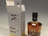 the bottle of rum is next to a cardboard box on a white surface