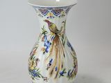 a vase with a bird on it sitting on a table