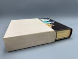 un livre ouvert posé sur une table, devant un fond gris
