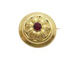 gros plan d'une bague en or avec une pierre rouge au centre