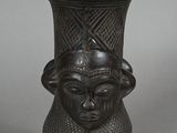 a black vase with a face on the top of it