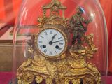 a gold clock under a glass dome on a table