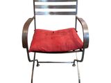 une chaise en métal sur laquelle est posé un coussin rouge