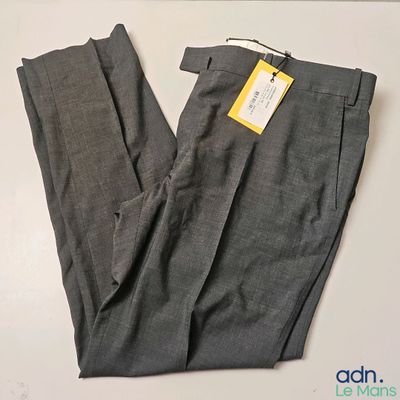 Le pantalon est gris et porte une étiquette jaune.