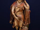 an antique wooden statue of a man holding a book on a rock